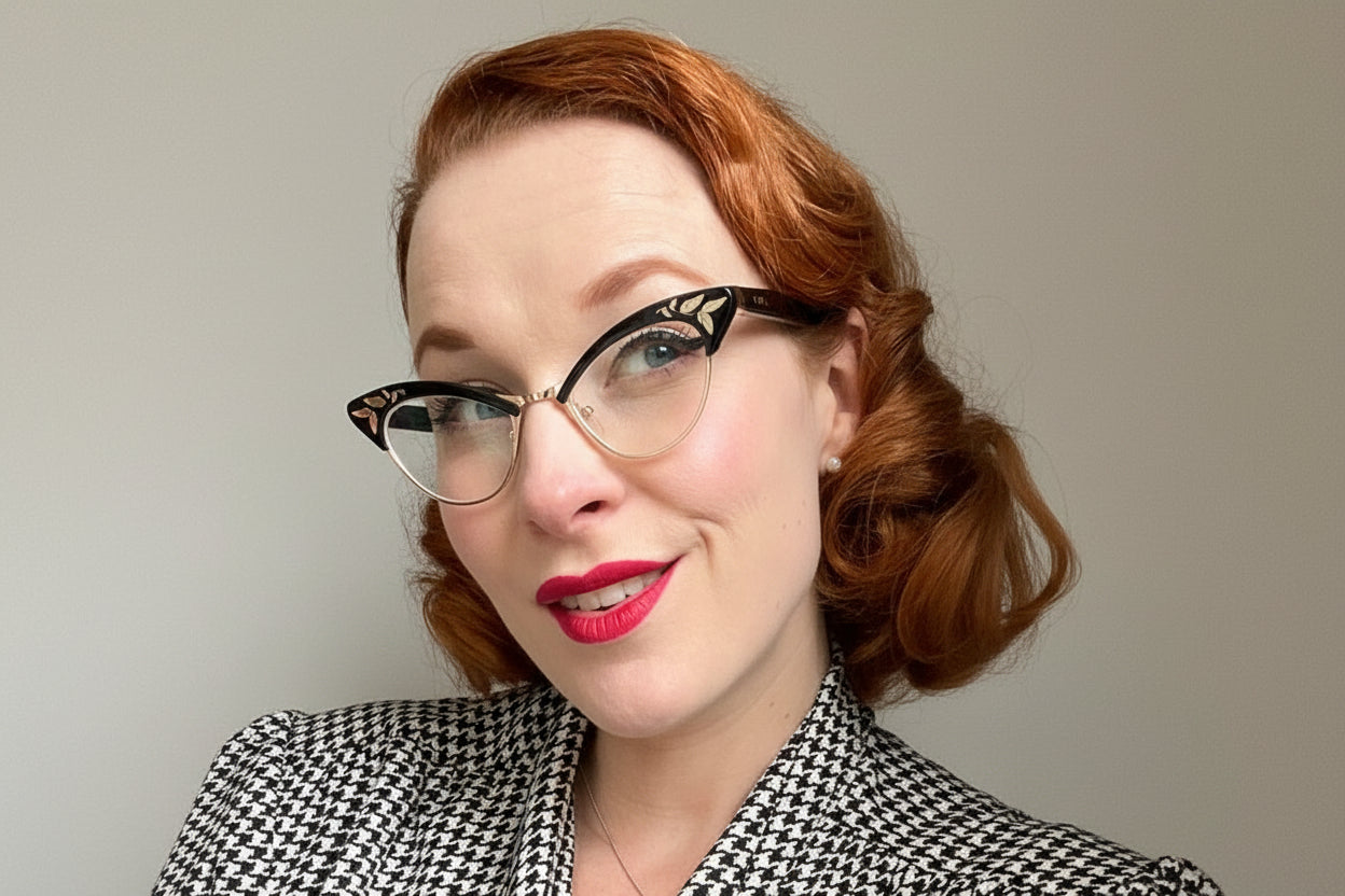 Woman wearing a black and white checkered blouse with vintage cat eye glasses.