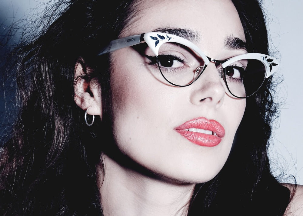 Close-up of a person wearing stylish vintage inspired glasses with a dark background